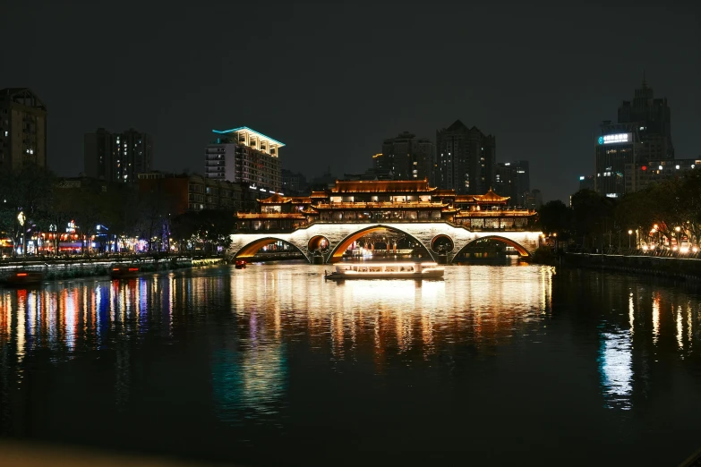 an old bridge and city lights are reflected in the water