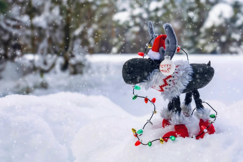 a mickey mouse dressed up in christmas attire and holding a light on top of a snow bank