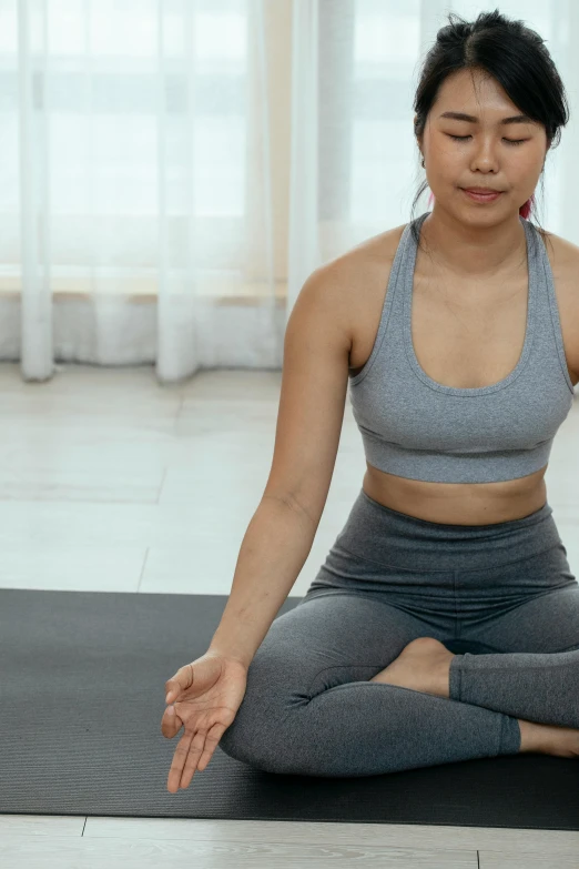 a woman practices yoga in front of a window