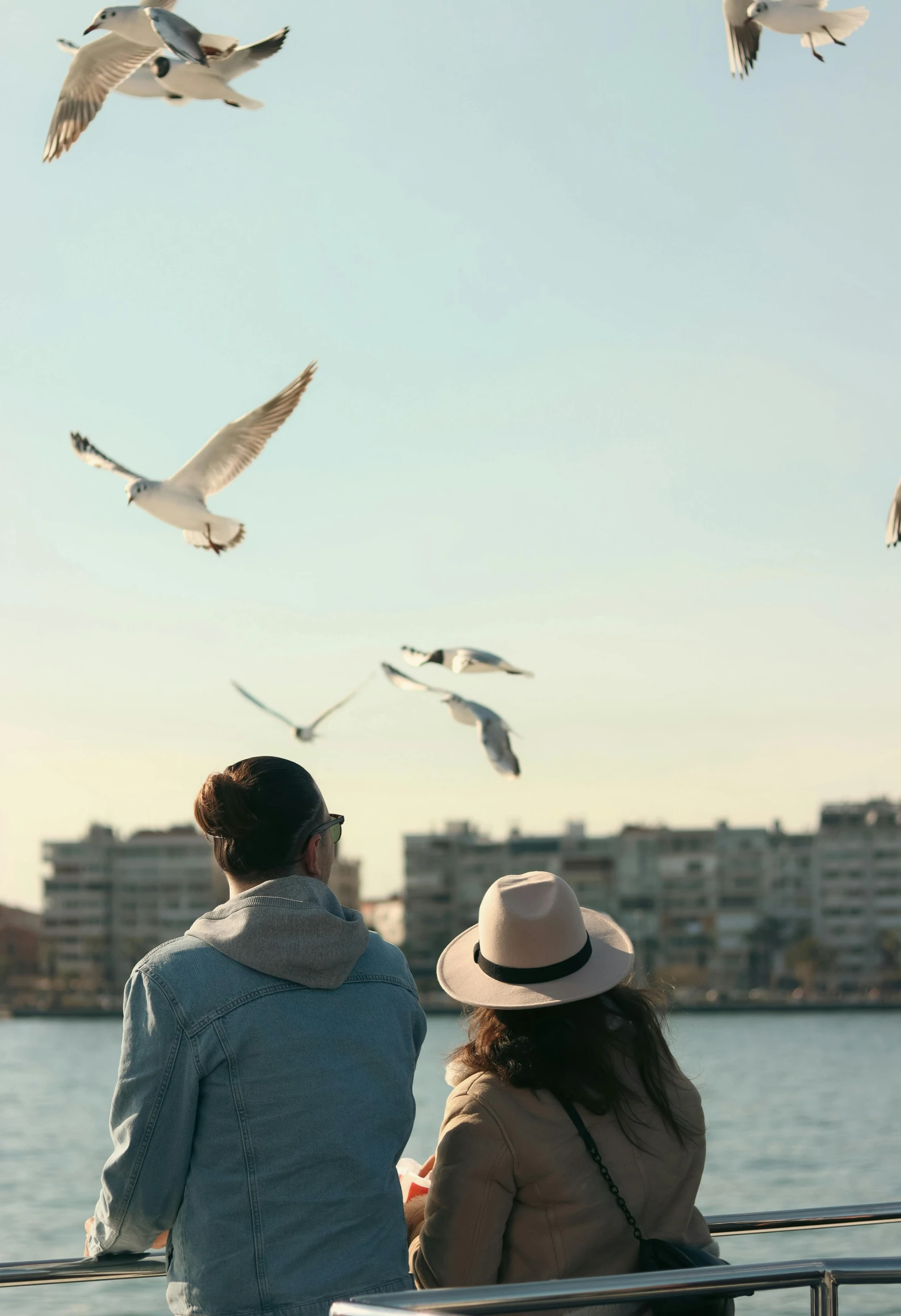 a man and woman watch birds flying over a body of water