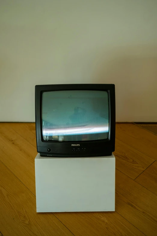 an old television on a white pedestal in a room