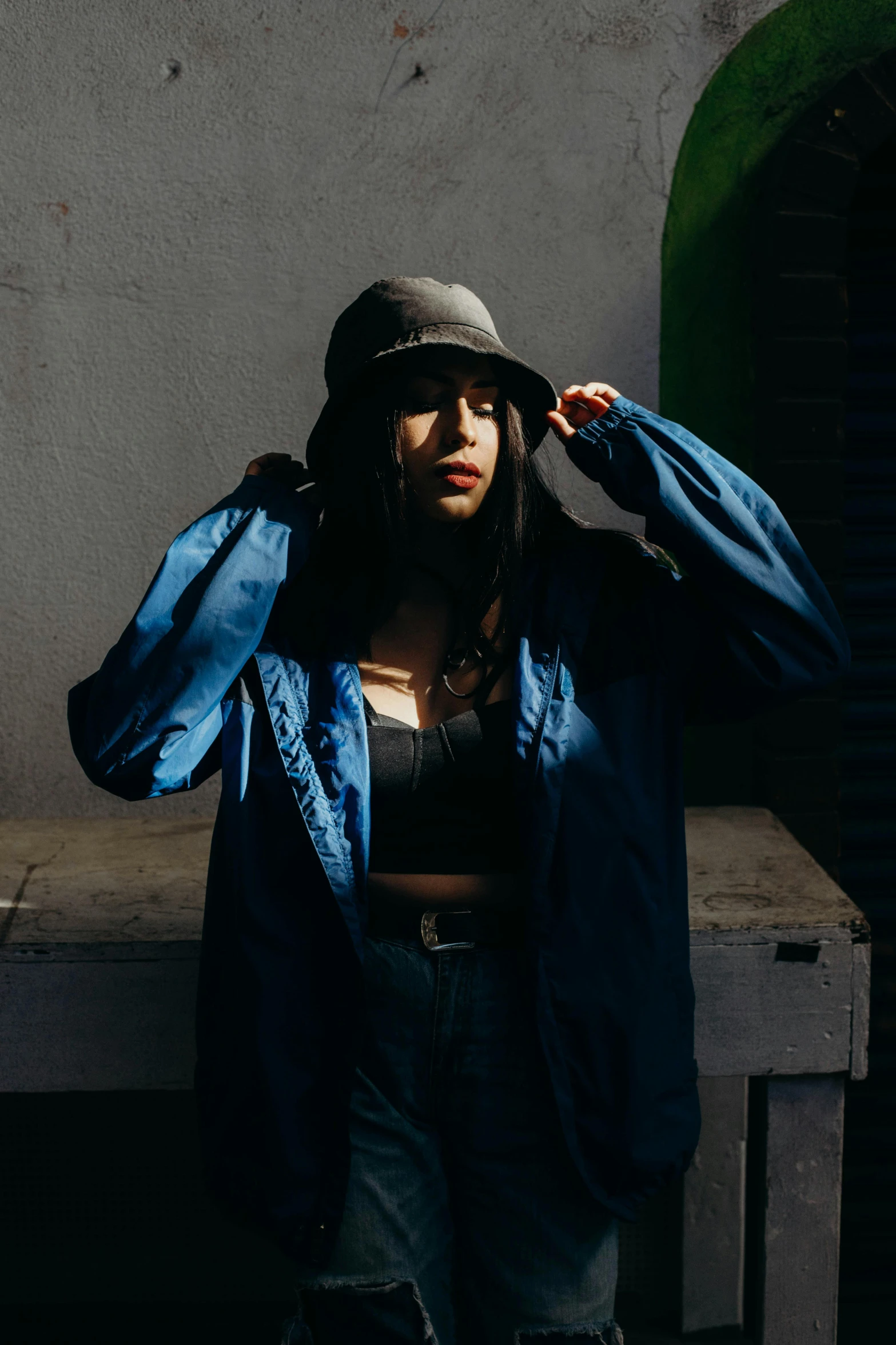 a young woman is holding her hat near her face