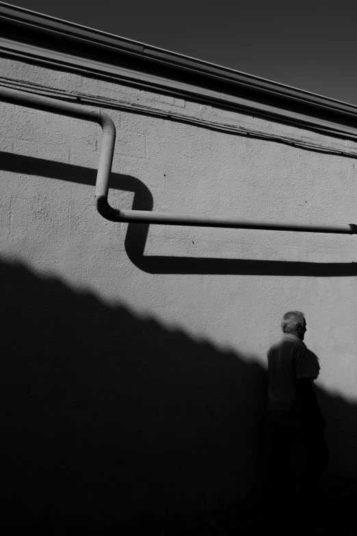 a black and white po of a man walking in front of a wall