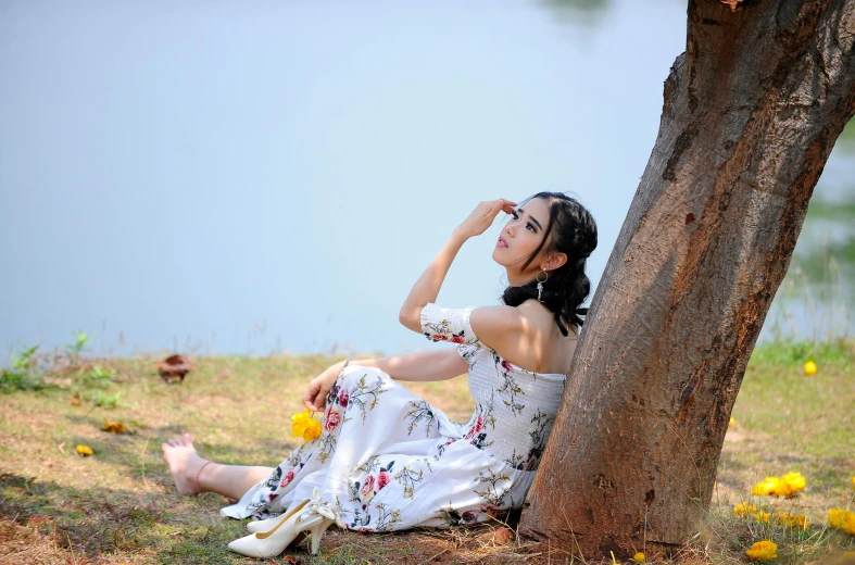 an asian girl is sitting against a tree