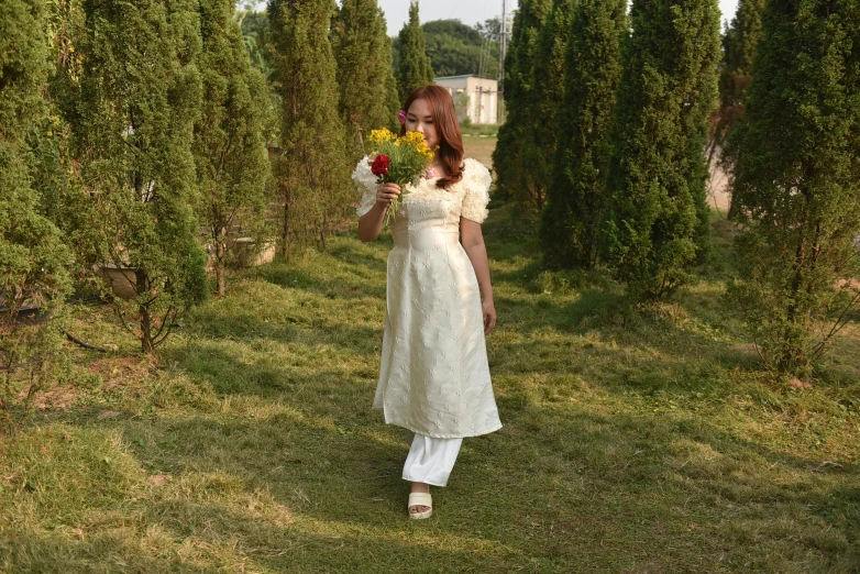 woman in white dress with yellow flowers walking by some trees