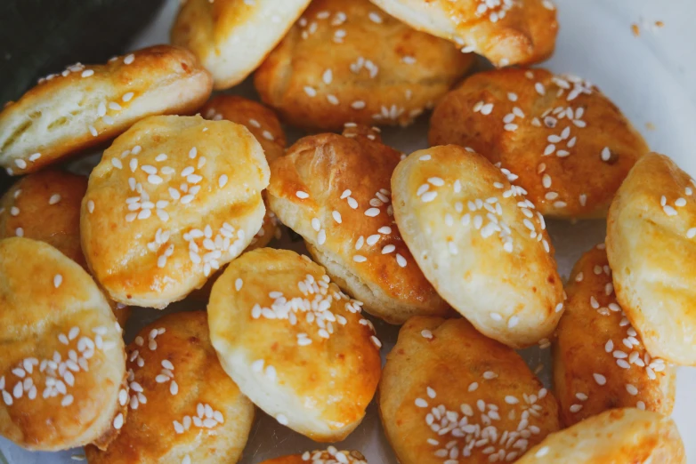 a plate full of small pastries, and some sesame seed on them