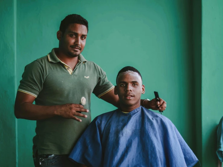 a man is getting his hair cut by another guy