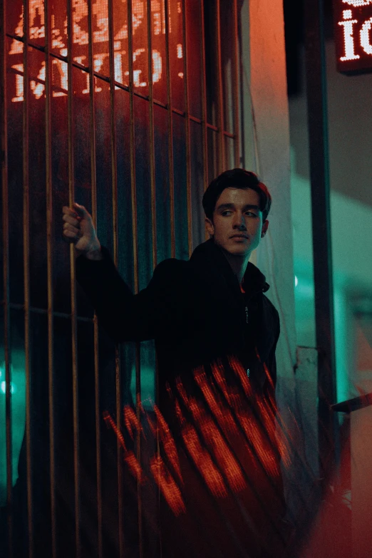 a man holding his hand through bars in front of a neon sign