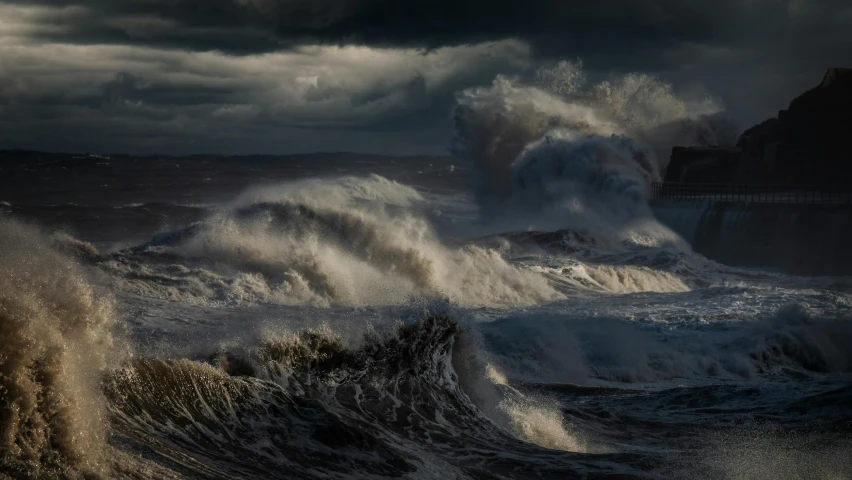 a big wave on the ocean near a rock wall