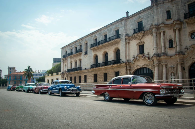 a row of classic cars line up in front of a building