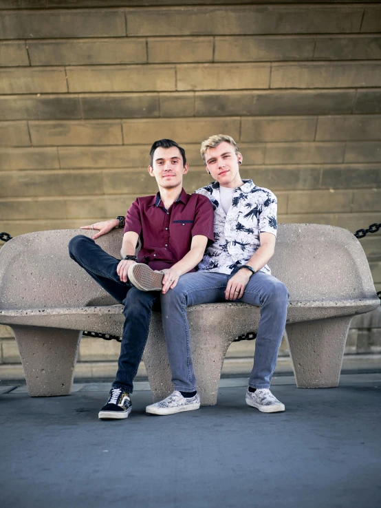 two males are sitting on the cement bench