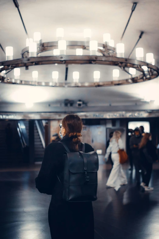 the woman is wearing a backpack in front of a ceiling light