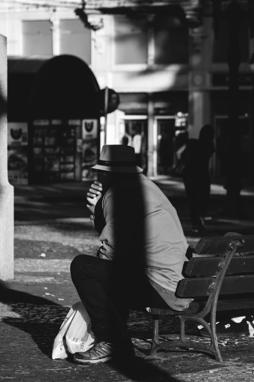 a man sits alone on a bench looking down