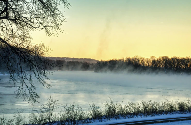 the sun is setting over a lake covered in snow