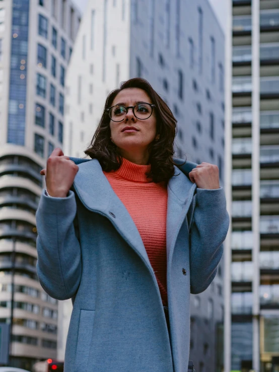 a beautiful woman wearing glasses standing next to buildings