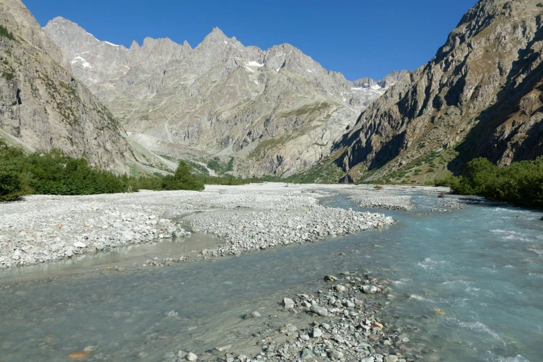 a river near some rocks with mountains in the background