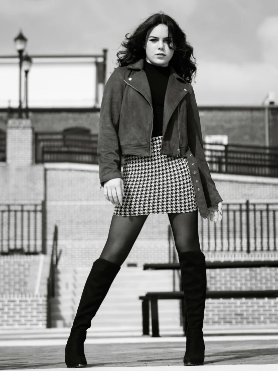 a woman wearing over - the - knee boots and a skirt