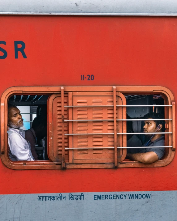 a red and gray train car with passengers on it