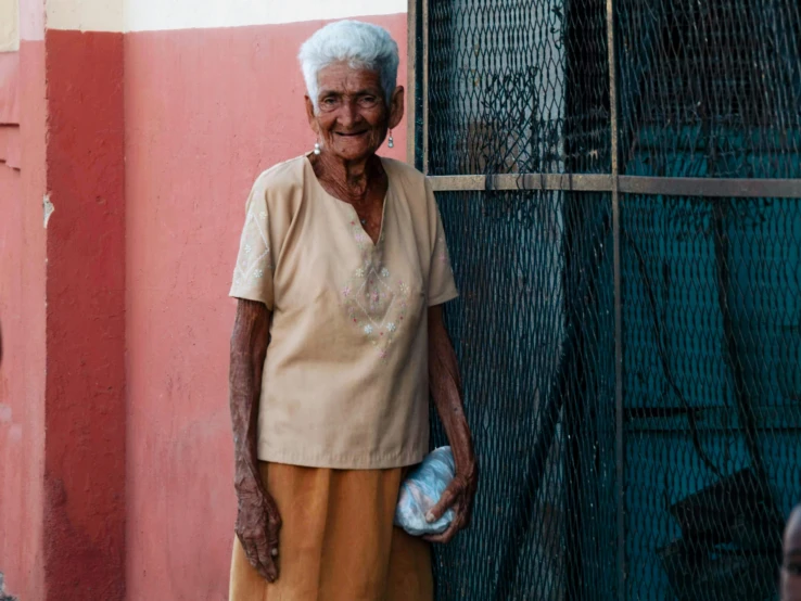 an older woman posing against a building wall