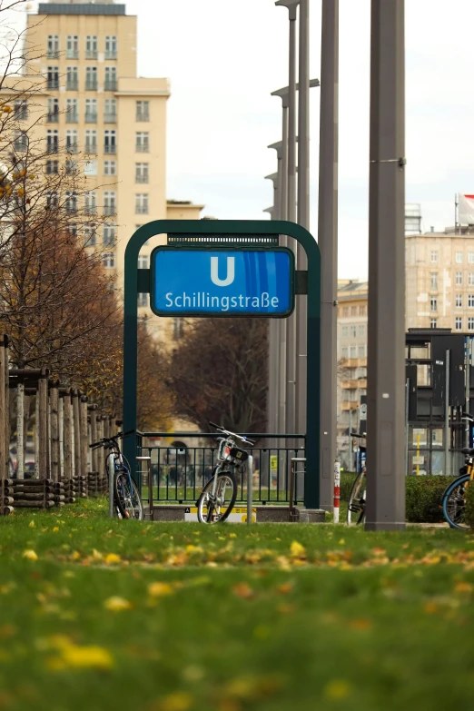 the city sign stands in front of some trees and bicycles