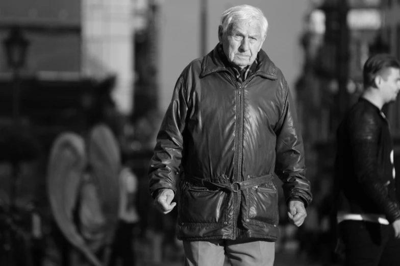 an older person wearing a leather jacket is walking along