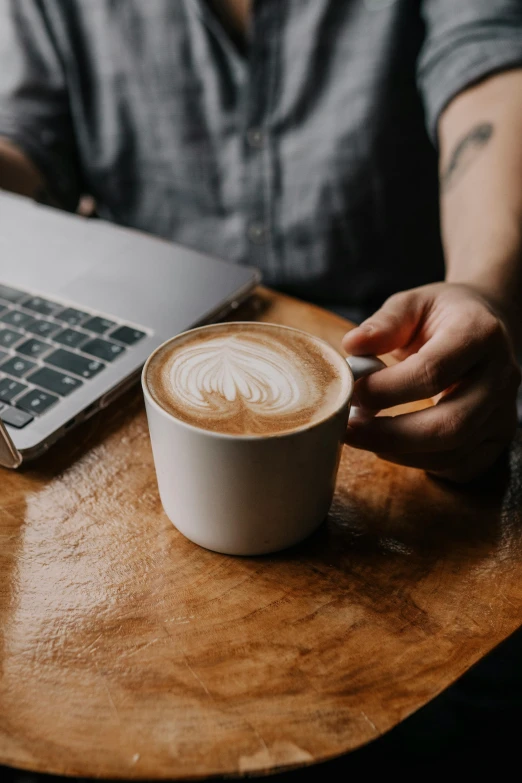 a man with a cup of coffee is on a table with his laptop