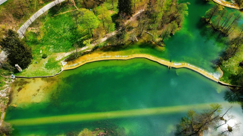 an aerial view of an area with water, trees and road