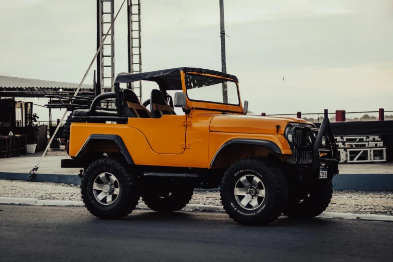 an orange jeep driving down a road next to a tall tower