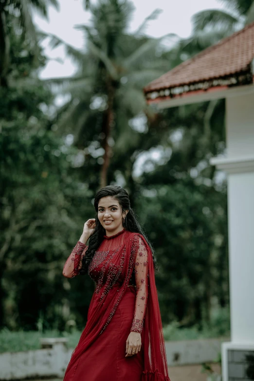 a beautiful indian woman in a maroon dress is posing