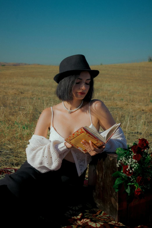 a woman wearing a hat and dress holding an open book