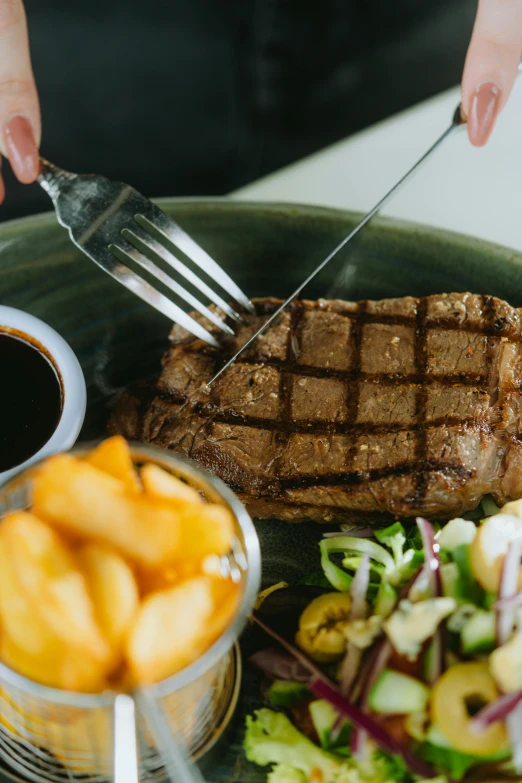 a person using tongs to cut into a steak