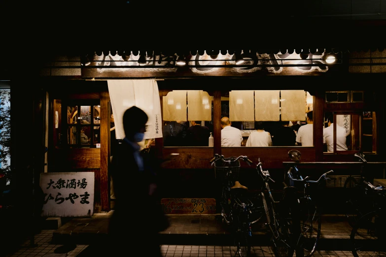 a dark street corner with a man walking by parked bikes