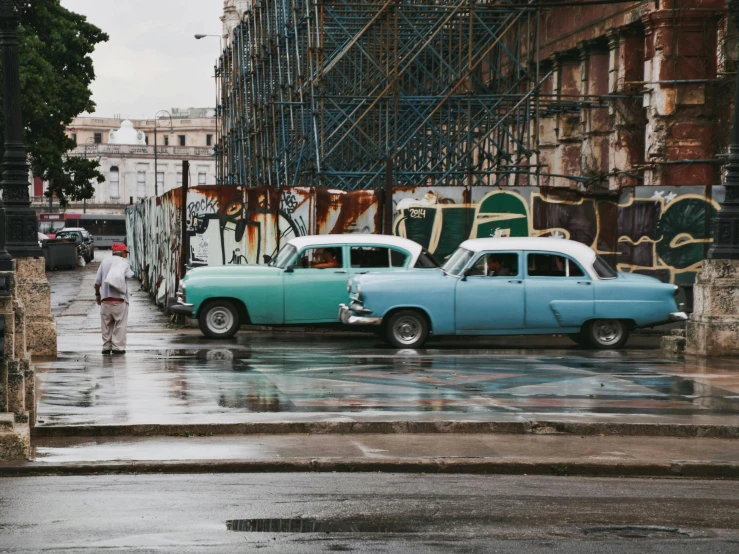 a couple of cars sit parked next to each other in front of an old building