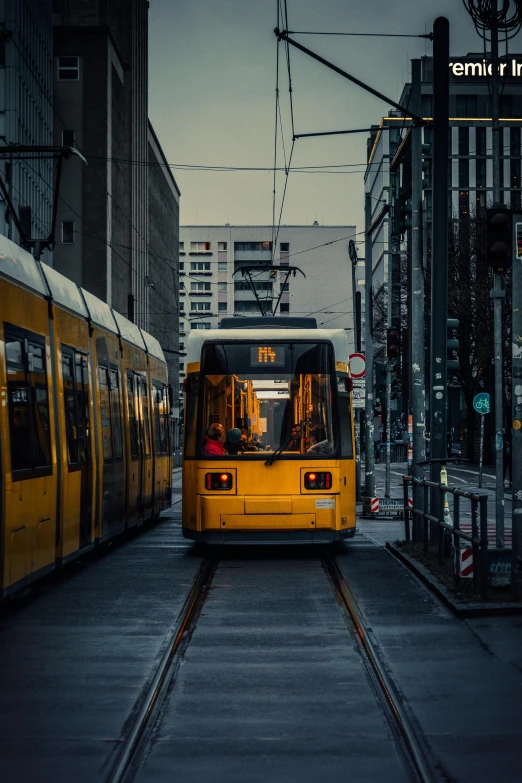 a large yellow tram is driving past a building