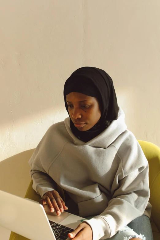 a woman is using a computer on a yellow chair