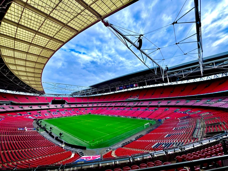 an empty stadium with red seats and some blue sky