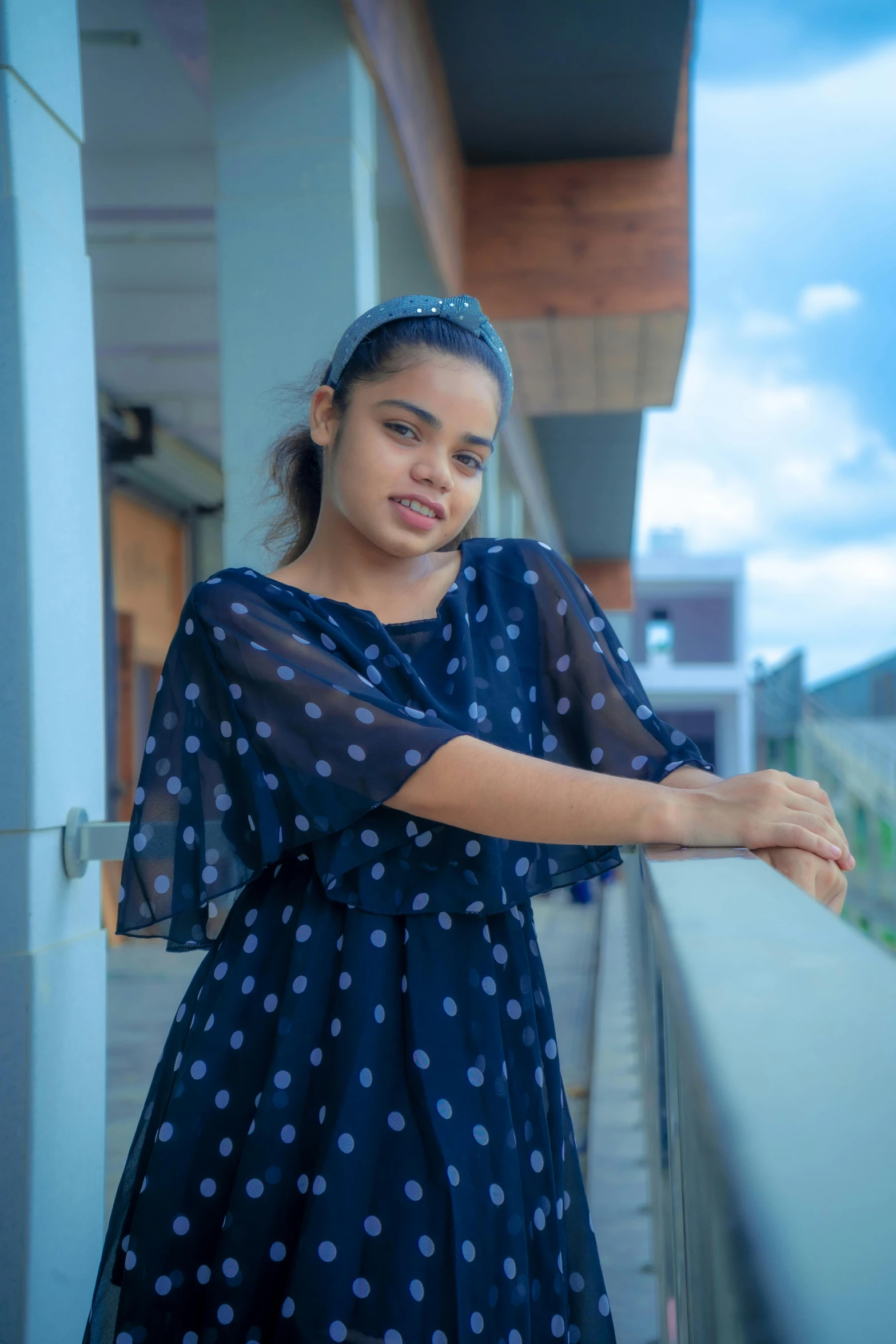 a girl leaning on the edge of a wall near the rail