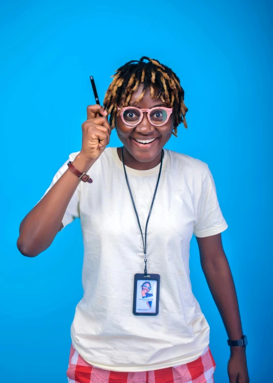 a young person standing in front of a blue wall holding a pair of scissors