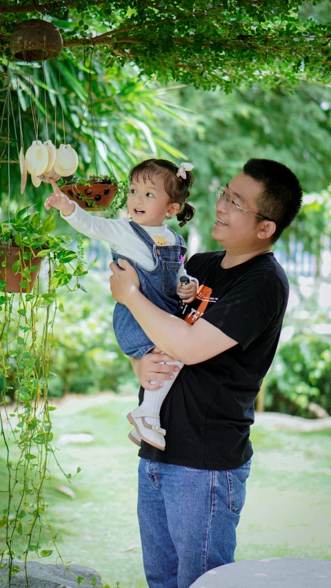 a father holds his daughter under a tent at the park