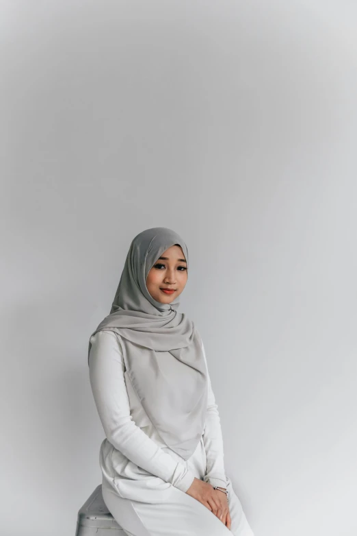 a woman is sitting on a stool in a white outfit