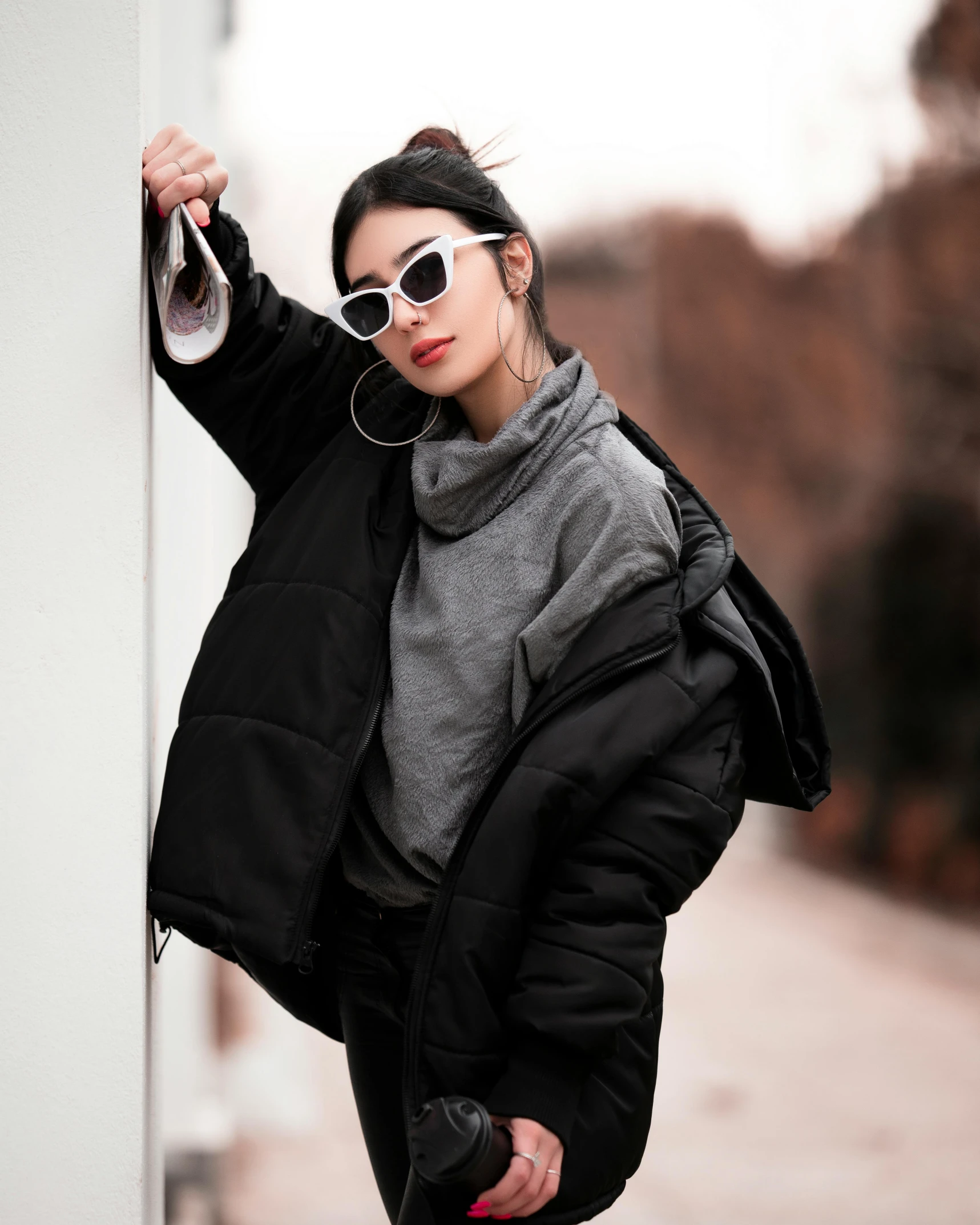 woman leaning on a wall wearing sunglasses with headphones