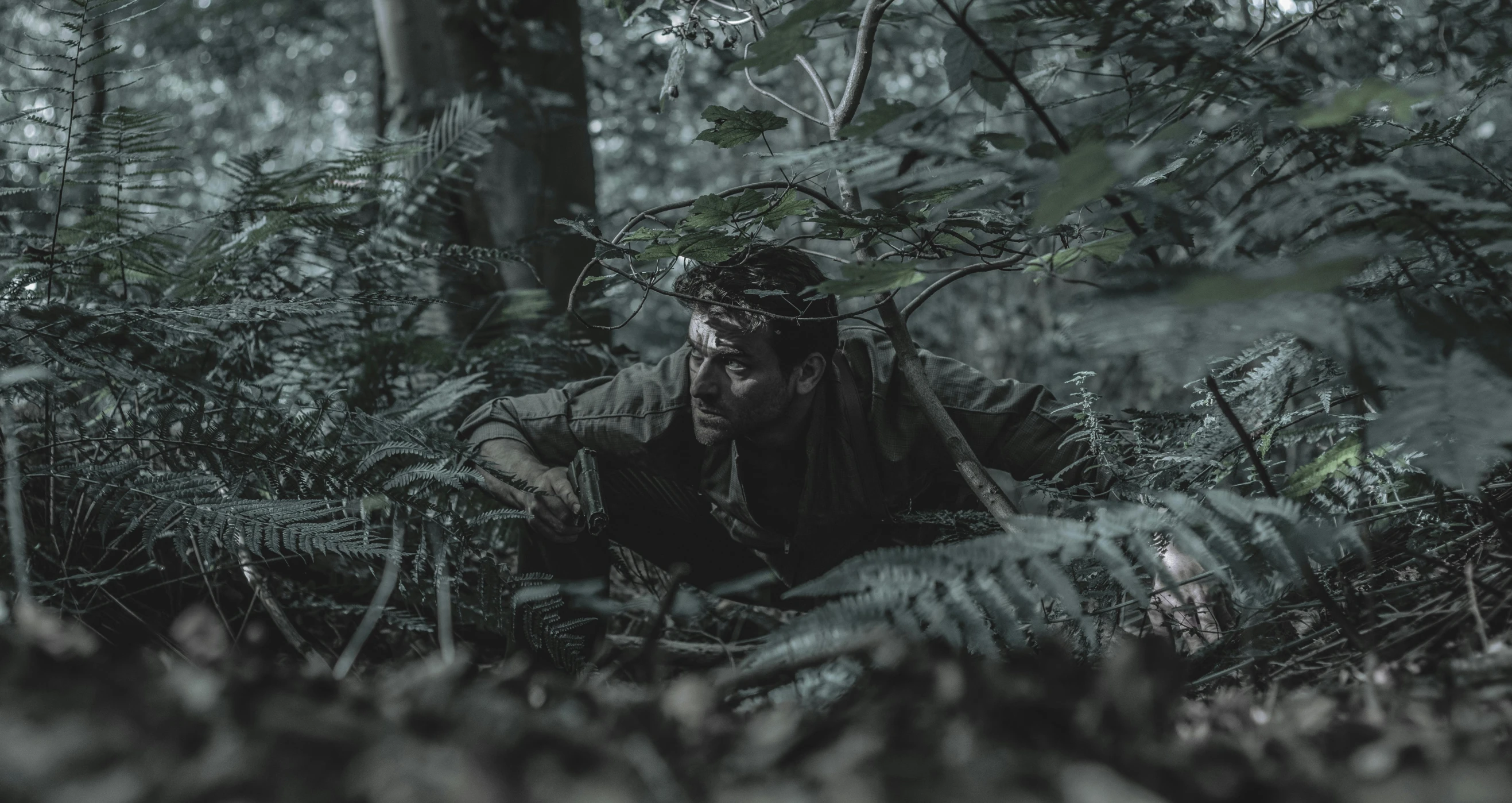 the man is squatting in the middle of a forest