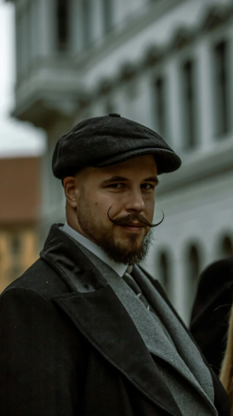 a man wearing a black hat and a gray blazer