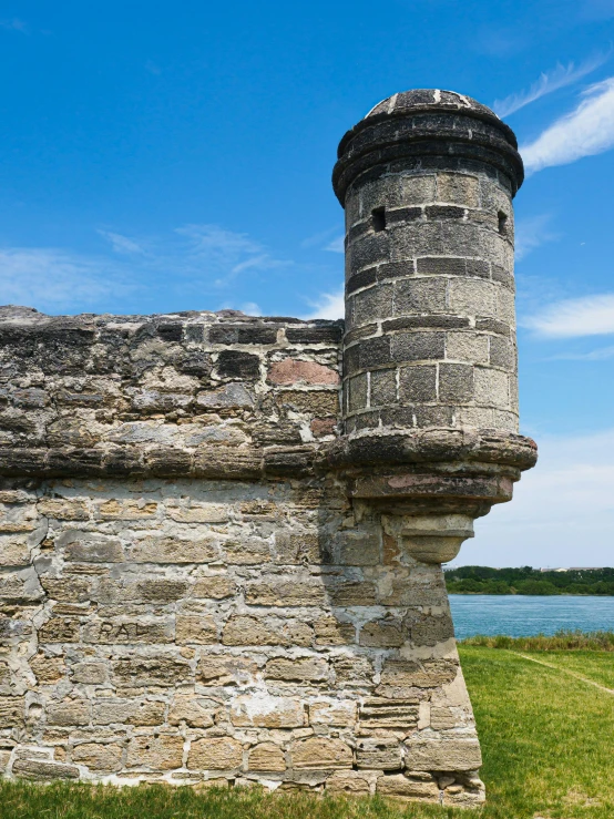 a stone wall with grass and a blue sky