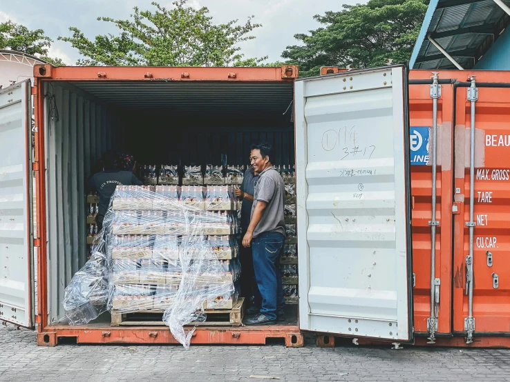 man standing in open shipping container filled with various items