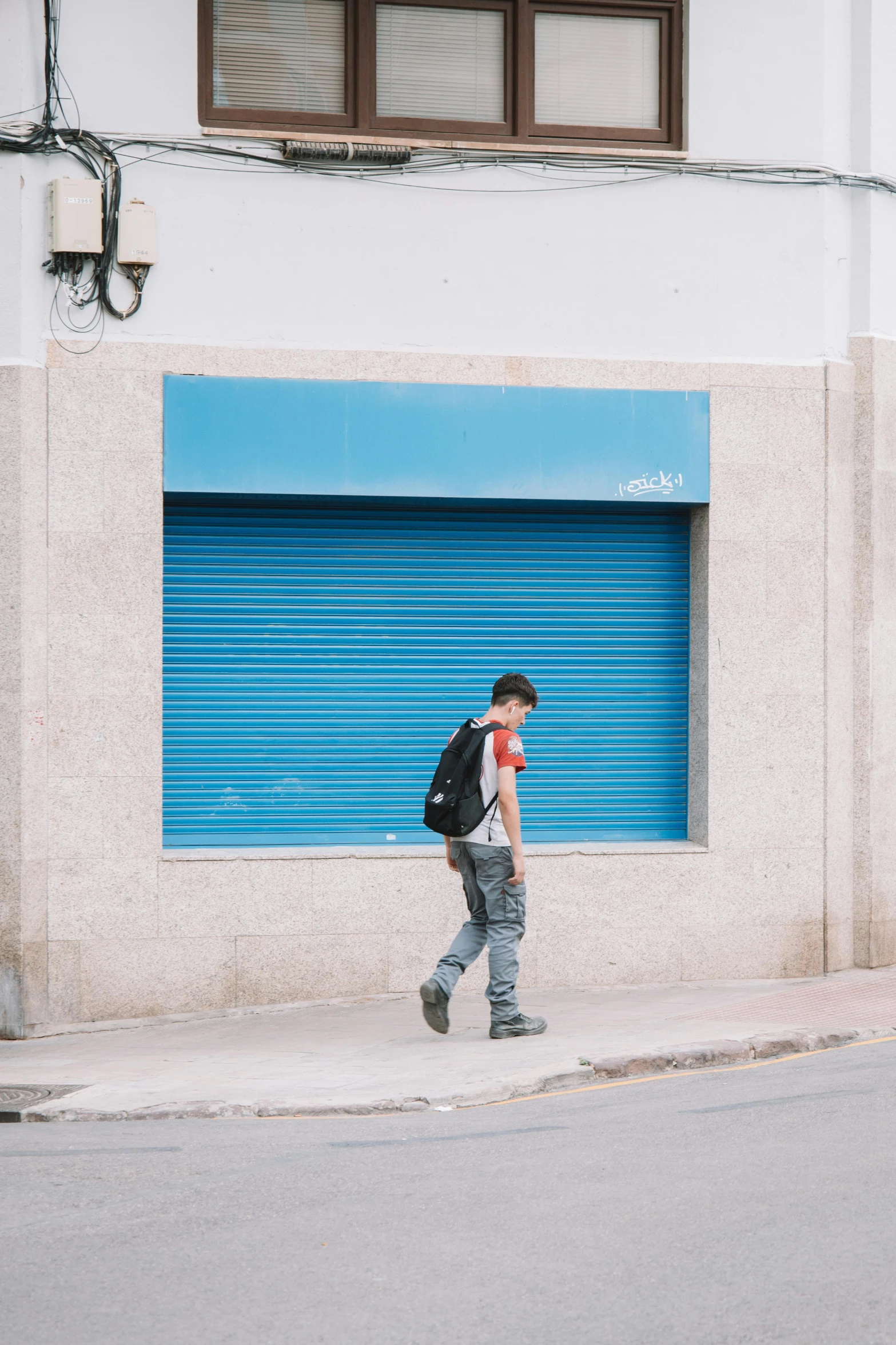 a boy walking on a sidewalk near a street