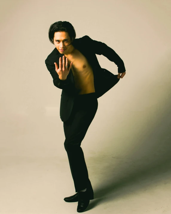 a man in black posing with his shirt over his chest