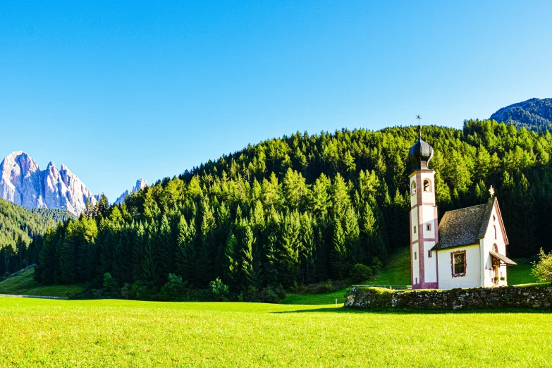 a small white church sitting next to a lush green hillside