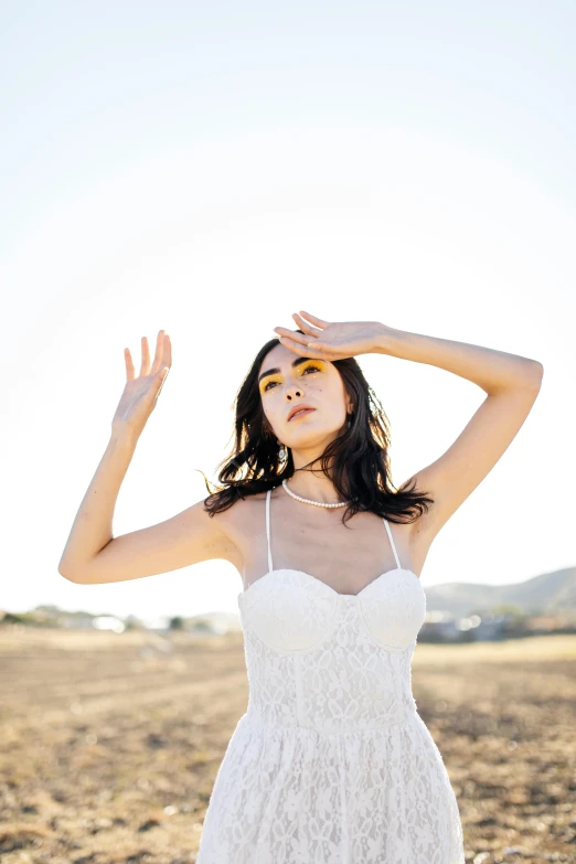 a woman wearing a white dress posing for the camera