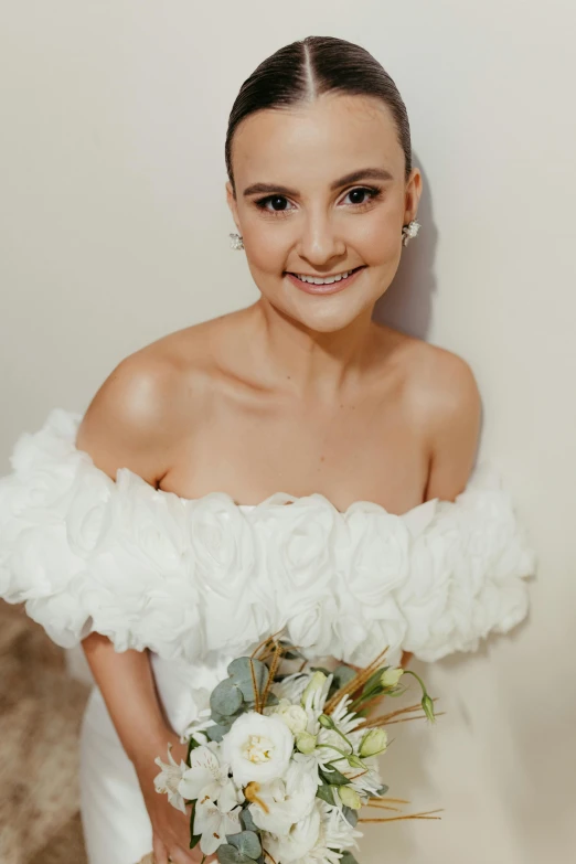 a woman smiling for a pograph in a wedding gown with flowers and greenery